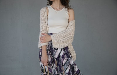 Woman wearing a white vest and gray flower skirt
